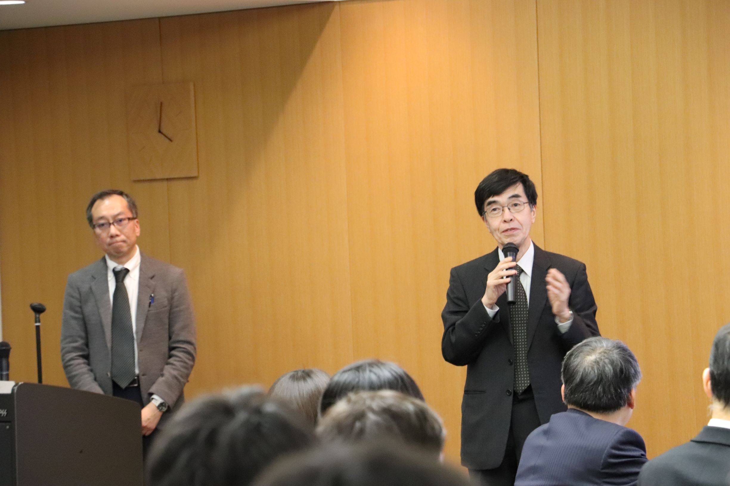 写真１ 挨拶を行う小長井委員長（右）と司会の岡田幹事長（左）